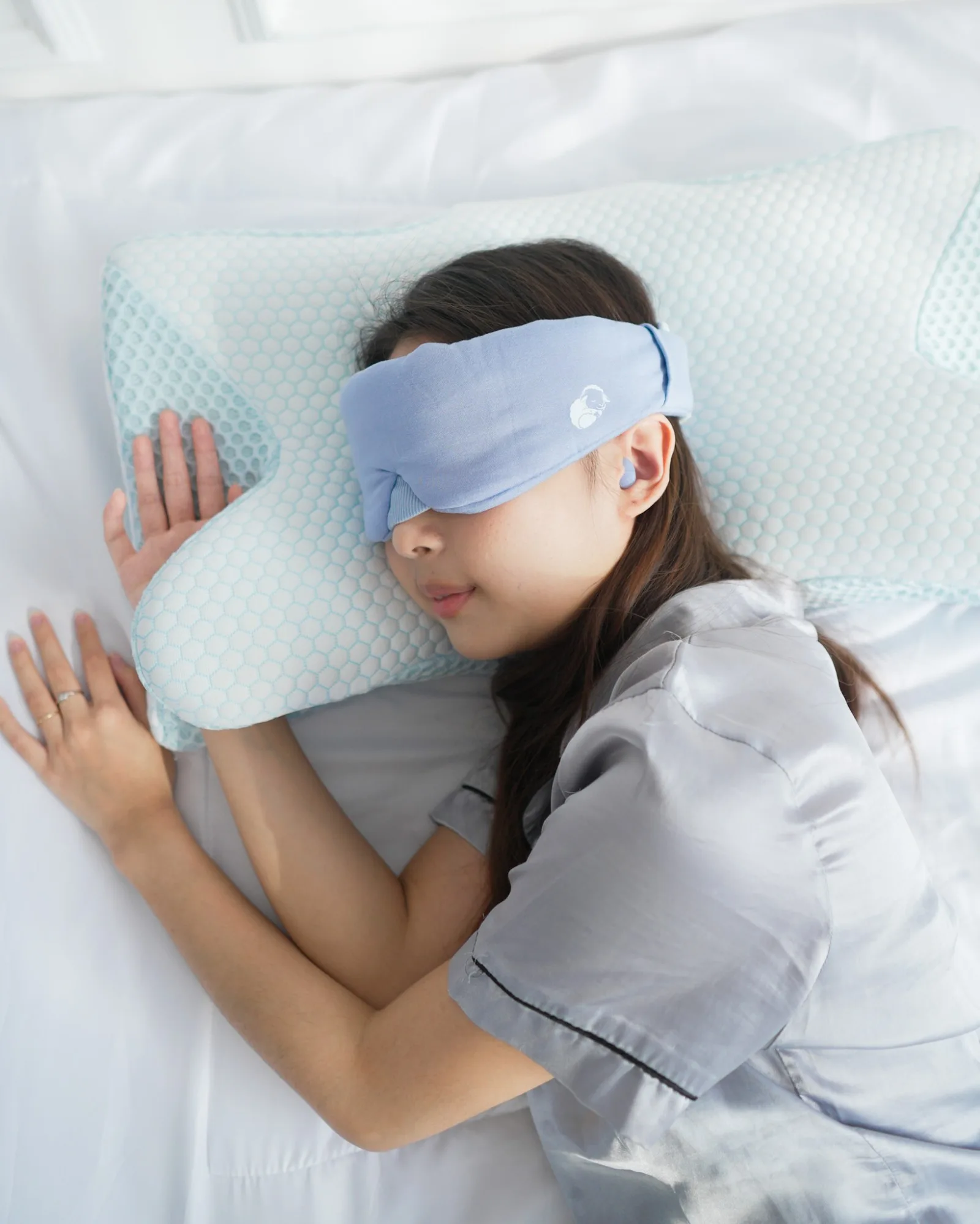 Perempuan tidur nyenyak memakai LumiCloud di atas bantal CerviCloud